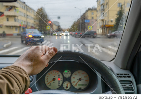 driver hand on the steering wheel inside the car while parking at a traffic light driver hand on the steering wheel inside the car while parking at a traffic light 78186572