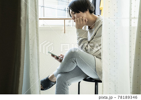 ベランダでスマホを見る男性 78189346