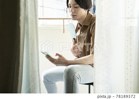 ベランダでスマホを見る男性 78189372