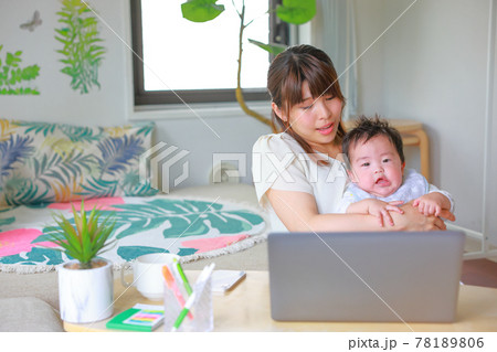 暴れる乳児に困惑するテレワークの母親の写真素材