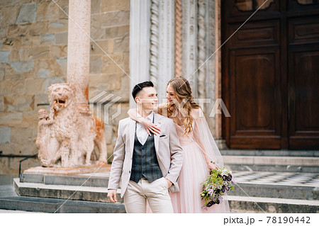 Bride with a bouquet of flowers hugs shoulders of smiling groom on the steps at the entrance to the Basilica of Santa Maria Maggiore in Rome Bride with a bouquet of flowers hugs shoulders of smiling groom on the steps at the entrance to the Basilica of Santa Maria Maggiore in Rome 78190442