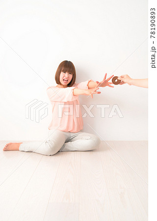 おやつを奪われ困惑する若い女性 78190893