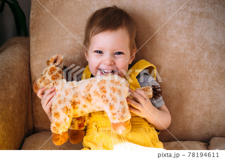 Funny little child is having fun, playing with soft toys on the couch at home. 78194611