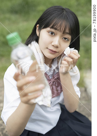 夏の野外で休憩する女子高生の写真素材
