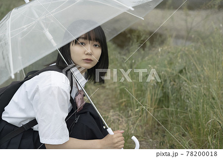 河原で傘をさす女子高生の写真素材