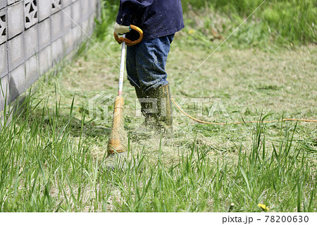 家庭用電動草刈機で庭の草刈りをする中年女性の足元 家庭用電動草刈機で庭の草刈りをする中年女性の足元 78200630