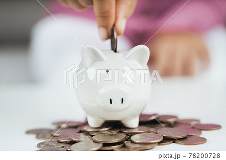 Close up of woman hand putting money coin into piggy bank for saving money. saving money and financial concept Close up of woman hand putting money coin into piggy bank for saving money. saving money and financial concept 78200728