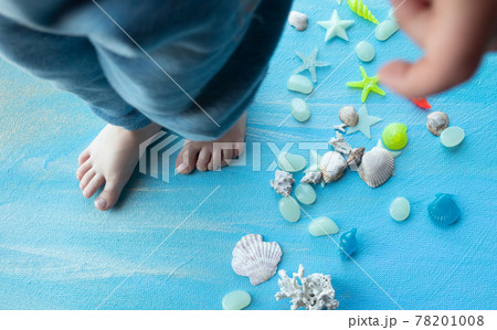 baby feet on Seashells summer background. Many different seashells, starfish on a background of blue paint strokes. Place for text. 78201008