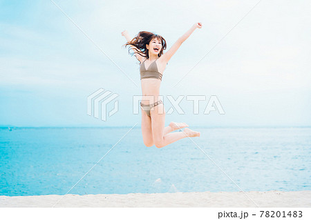 砂浜でジャンプする水着の女性 78201483