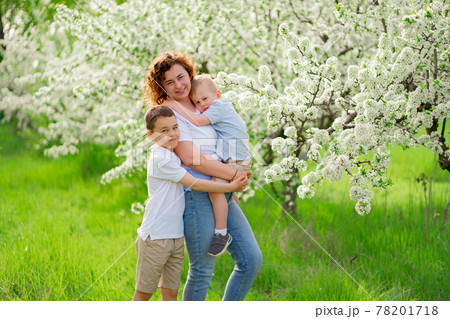 mother with sons in flowering garden. youngest child in her arms 78201718