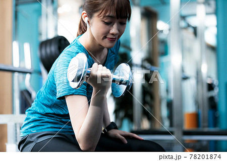 貸し切りのフィットネスジムで筋トレする若い女性 78201874