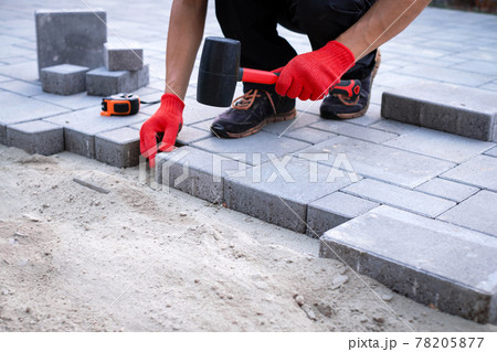 The master in yellow gloves lays paving stones 78205877