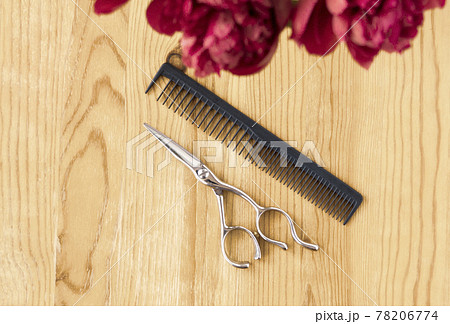 Barber scissors and comb on a wooden table, top view. Flat lay with tools and flowers. Barber scissors and comb on a wooden table, top view. Flat lay with tools and flowers. 78206774