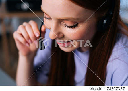 Close-up face of cheerful young woman operator using headset during customer support at home office. 78207387