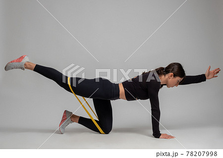Woman doing Dandayamana Bharmanasana with resistance band on grey background Woman doing Dandayamana Bharmanasana with resistance band on grey background 78207998