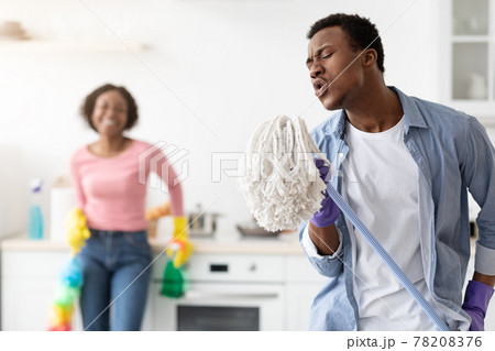 Funny black guy using mop as microphone, singing while cleaning Funny black guy using mop as microphone, singing while cleaning 78208376