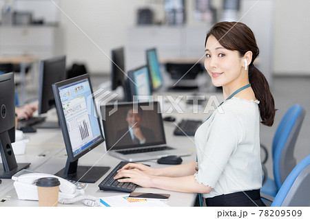 オフィスでオンラインで話をしながらパソコン操作をする若いビジネスウーマンのポートレート 78209509