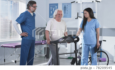 Rehabilitation therapists helping elderly patient to walk on treadmill 78209545