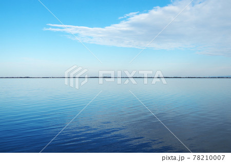 無風で波の静かな中海の水面に青い空と白い雲が映って横一文字の弓ヶ浜で天地を仕切られている幻想的な風景 78210007