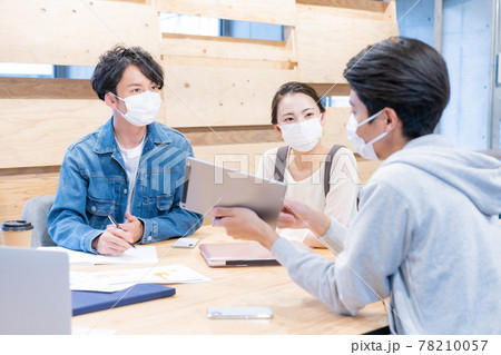 オフィスでマスクをしながらミーティングをするマ若い男女3人 78210057