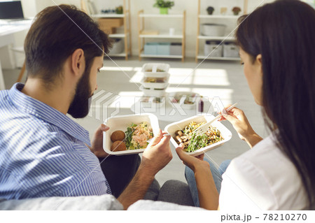 Young couple man and woman office workers sitting and enjoying healthy boxed food order 78210270