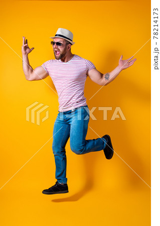 Excited young bearded fitness sporty guy in hat and sunglasses Jump very emotionally isolated on yellow background Excited young bearded fitness sporty guy in hat and sunglasses Jump very emotionally isolated on yellow background 78214173