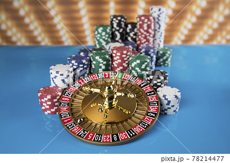 Poker Chips on gaming table, roulette wheel in motion, casino background 78214477