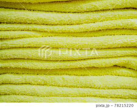 Yellow terry identical towels are stacked in a stack. Background texture. Full-screen photos Yellow terry identical towels are stacked in a stack. Background texture. Full-screen photos 78215220