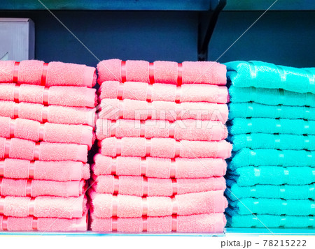 Stacks of pink and turquoise terry towels are stacked on a shelf on a blue background Stacks of pink and turquoise terry towels are stacked on a shelf on a blue background 78215222