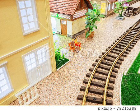 Miniature railway with small houses and little men on a bench 78215288