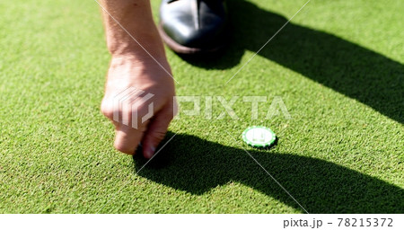 Close up shot of unrecognizable male golf player setting mark and repairing pitch mark on green grass of course 78215372