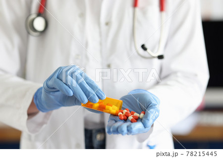 Doctor with medical gloves sprinkles pills on hand Doctor with medical gloves sprinkles pills on hand 78215445