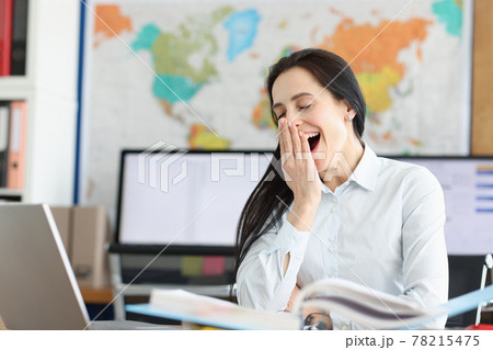 Young woman yawns at workplace for laptop Young woman yawns at workplace for laptop 78215475
