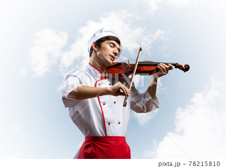 Young male chef playing violin 78215810