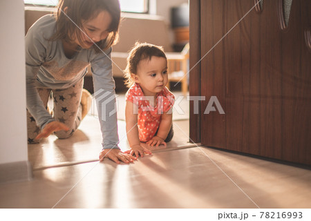 Girl play with her little sister at home. They have fun when walk on all fours 78216993