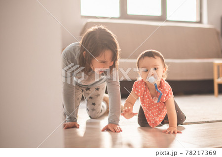 Girl play with her little sister at home. They have fun when walk on all fours 78217369