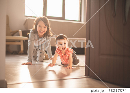 Girl play with her little sister at home. They have fun when walk on all fours Girl play with her little sister at home. They have fun when walk on all fours 78217374