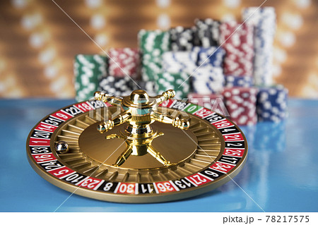 Poker Chips on gaming table, roulette wheel in motion, casino background 78217575