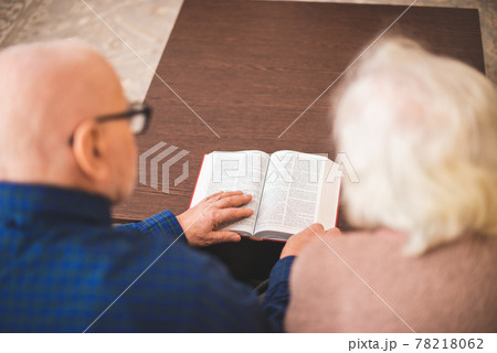 Elderly couple reading bible and pray together at home. Elderly couple reading bible and pray together at home. 78218062