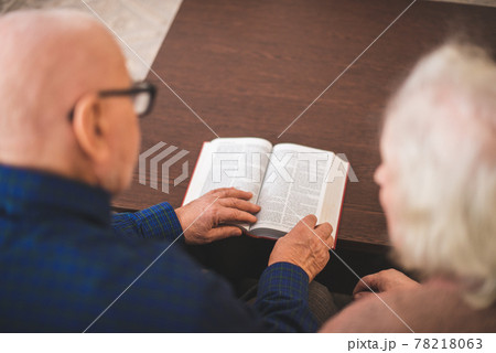 Elderly couple reading bible and pray together at home. Elderly couple reading bible and pray together at home. 78218063