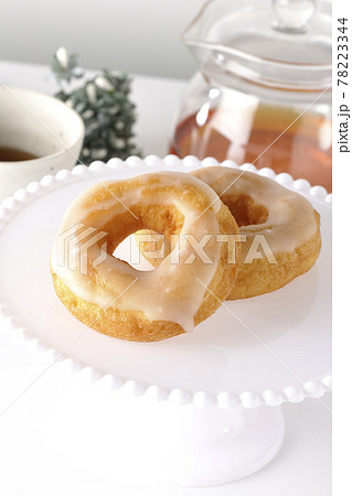 アフタヌーン ティー ケーキスタンドに盛り付けられたハニーグレーズドーナツとティーポットの写真素材