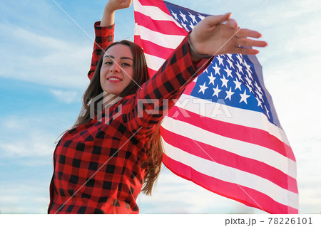 Young millennial brunette woman holding The National Flag of USA. American Flag. Tourist traveler or patriotism. Immigrant in free country. July 4th Independence Day. Caucasian Young millennial brunette woman holding The National Flag of USA. American Flag. Tourist traveler or patriotism. Immigrant in free country. July 4th Independence Day. Caucasian 78226101