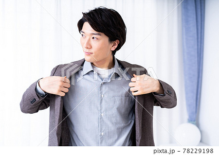リビングでスーツの上着を着る男性 78229198
