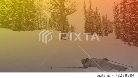 Composition of skier lying in snow in mountains with orange tint 78229984