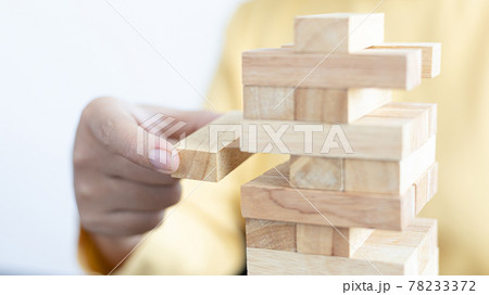 Business growth with wooden blocks concept, Planning to Reduce Investment Risks with Wooden Game Models, hand of a business woman placed a wooden block on a high tower,Management of limited resources. Business growth with wooden blocks concept, Planning to Reduce Investment Risks with Wooden Game Models, hand of a business woman placed a wooden block on a high tower,Management of limited resources. 78233372