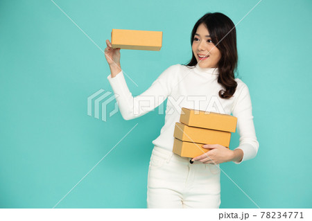 Happy Asian woman smiling and holding package parcel box isolated on light green background, Delivery courier and shipping service concept 78234771