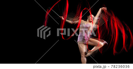 One femalel rhythmic gymnast in motion and action isolated in mixed light on dark background. Flyer 78236036
