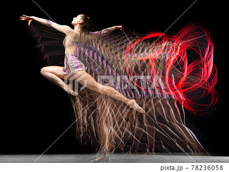 Young graceful girl rhythmic gymnast in motion isolated in mixed light on dark background. 78236058
