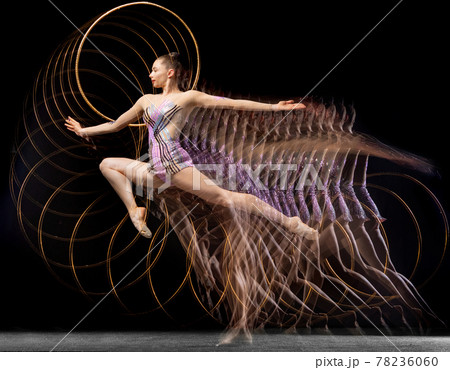 Portrait of young girl rhythmic gymnast in motion and action isolated in mixed light on dark background. 78236060