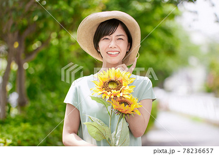 ひまわりの花を持つ笑顔の若い女性の写真素材